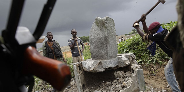 April 10: A soldier allied with Alassane Ouattara knocks down a monument believed to mystically provide strength and support to Laurent Gbagbo, in the Youpougon neighborhood of Abidjan, Ivory Coast.