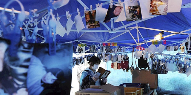 April 11: A survivor checks a personal item as photos found in the rubble hang down from ropes in Kesennuma, Miyagi Prefecture, northeastern Japan, one month to the day after an earthquake and tsunami devastated the city.