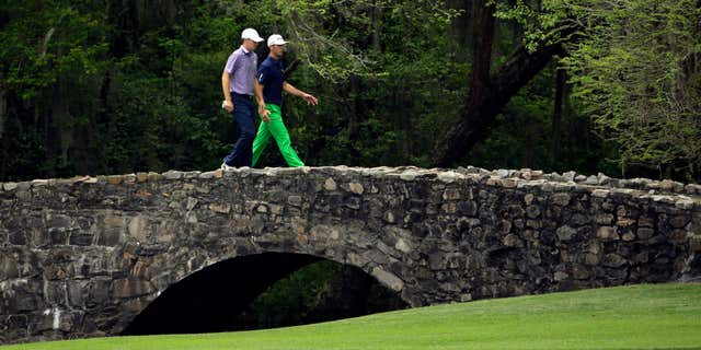 April 10, 2015: Jordan Spieth, left, walks over the Nelson Bridge with Billy Horschel during the second round of the Masters golf tournament.