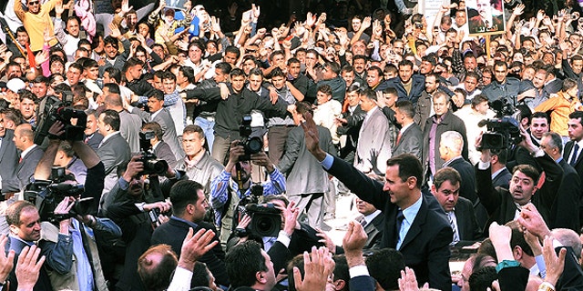 March 30: In this photo released by the Syrian official news agency SANA, Syrian President Bashar Assad, foreground right, waves to his supporters after he made a speech at the Parliament, in Damascus, Syria.