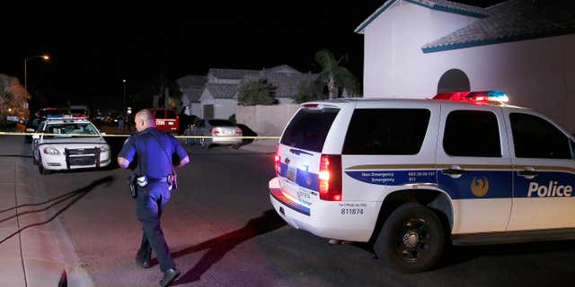 April 16, 2015: A Phoenix Police officer walks in front of the blocked off street near a home where authorities say five people were killed inside after a shooting.