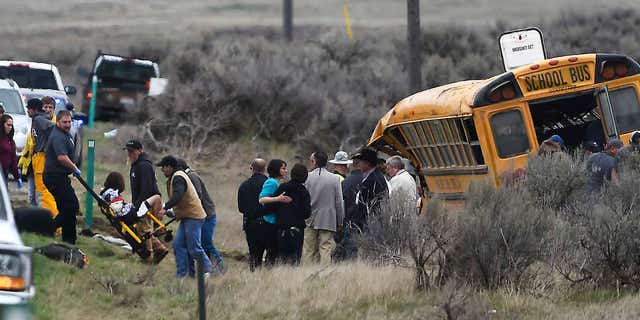 Emergency personnel help to remove passengers after school bus that Tuesday, April 18, 2017, west of Richfield, Idaho.