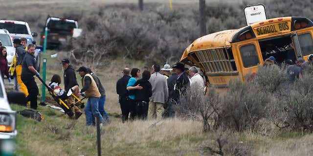 Emergency personnel help to remove passengers after school bus that Tuesday, April 18, 2017, west of Richfield, Idaho.