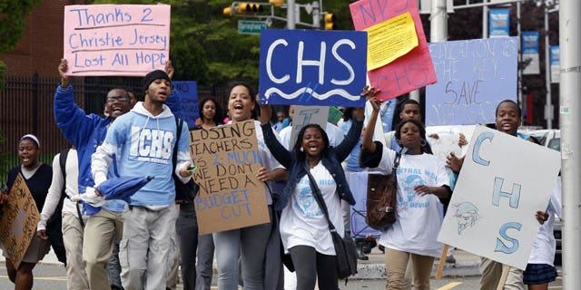 Cental High School students hold signs as they march to administrative offices in Newark, N.J., at about 11 a.m., Tuesday, April 27, 2010, after walking out of classes.