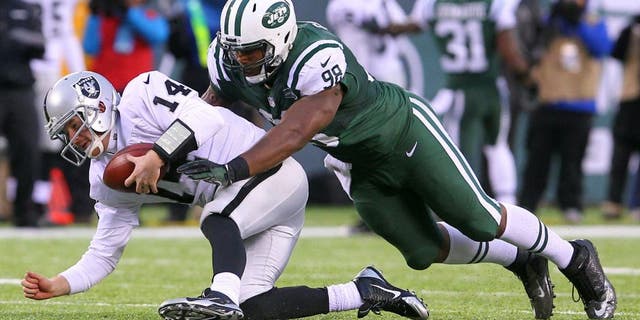 Dec 8, 2013; East Rutherford, NJ, USA; Oakland Raiders quarterback Matt McGloin (14) recovers his own fumble while being tackled by New York Jets defensive end Quinton Coples (98) during the second half at MetLife Stadium. The Jets defeated the Raiders 37-27. Mandatory Credit: Ed Mulholland-USA TODAY Sports