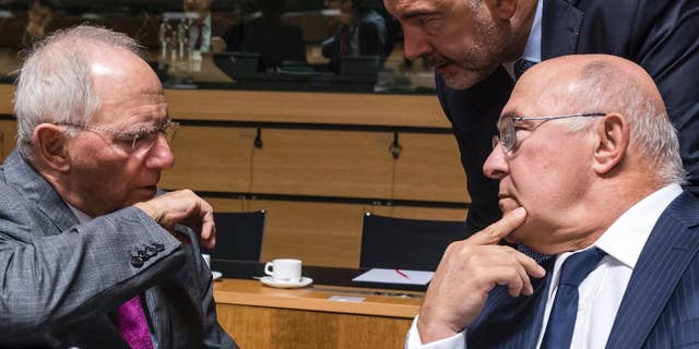 German Finance Minister Wolfgang Schauble, left, talks with Franch Finance Minister Michel Sapin, right, and European Commissioner for Economic Affairs, Taxation and Customs Pierre Moscovici during an EU finance ministers meeting at the EU Council in Luxembourg Tuesday, Oct. 11, 2016. (AP Photo/Geert Vanden Wijngaert)