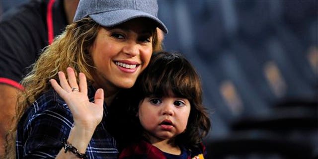 Colombian singer Shakira, left, waves with his son Milan prior of a Spanish La Liga soccer match between FC Barcelona and Eibar at the Camp Nou stadium against Eibar in Barcelona, Spain, Saturday, Oct. 18, 2014. (AP Photo/Manu Fernandez)