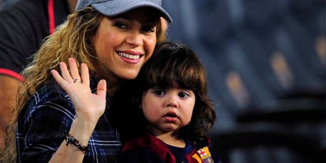 Colombian singer Shakira, left, waves with his son Milan prior of a Spanish La Liga soccer match between FC Barcelona and Eibar at the Camp Nou stadium against Eibar in Barcelona, Spain, Saturday, Oct. 18, 2014. (AP Photo/Manu Fernandez)