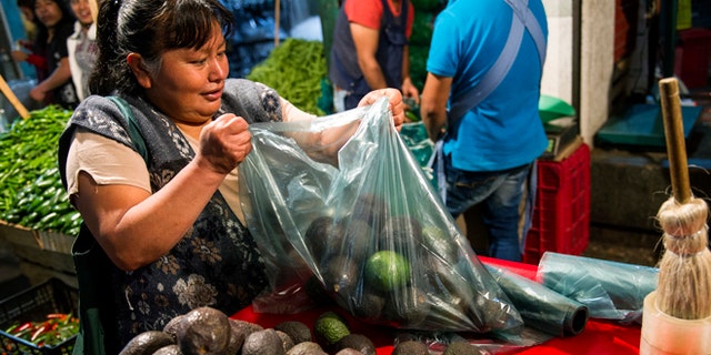 A woman prepares a bag of avocados in Mexico City, Tuesday, Aug. 9, 2016.