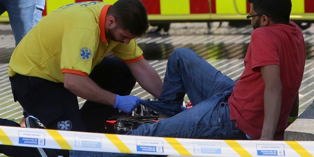 An injured person is treated in Barcelona, Spain, Thursday, Aug. 17, 2017 after a white van jumped the sidewalk in the historic Las Ramblas district, crashing into a summer crowd of residents and tourists and injuring several people, police said. (AP Photo/Oriol Duran)