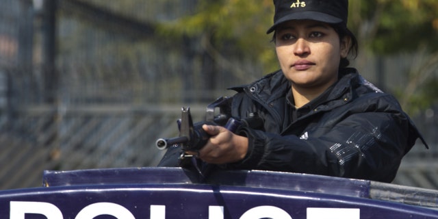 A Pakistani female police officer stands alert outside a court set up for the trial of Pakistan's former president and military ruler Pervez Musharraf in Islamabad, Pakistan, Wednesday, Jan. 1, 2014. Musharraf failed to appear in court Wednesday for the second hearing in his high-profile treason case after authorities said they found an explosive device near his home. (AP Photo/B.K. Bangash)