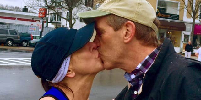 April 20, 2015: In this photo provided by Paige Tatge, her mother, Barbara Tatge, left, kisses an unknown spectator in Wellesley, Mass.
