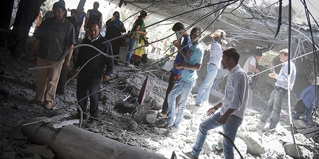 May 1: In this photo made on a government organized tour, supporters inspect damage at the Qaddafi family compound in a residential area of Tripoli, Libya.