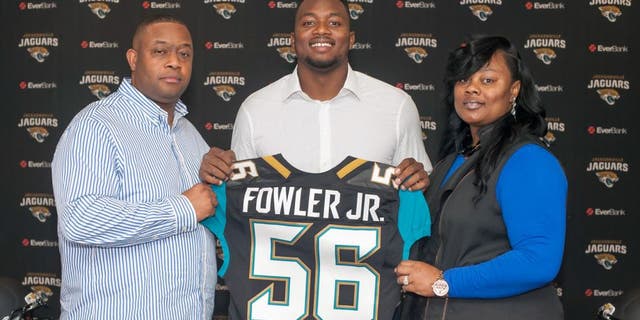 Dante Fowler, cener, the Jacksonville Jaguars first round draft pick, holds up his jersey as he stands between his parents Dante Fowler, Sr. and Lenora Fowler during an NFL football press conference at EverBank Field in Jacksonville, Fla., Saturday May 2, 2015. (Fran Ruchalski/The Florida Times-Union via AP)