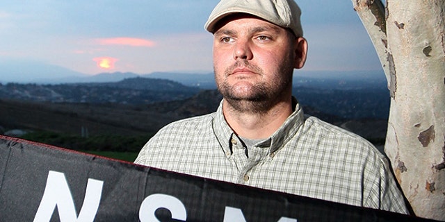 In this file photo taken Friday, Oct. 22, 2010, Jeff Hall holds a Neo Nazi flag while standing at Sycamore Highlands Park near his home in Riverside, Calif.