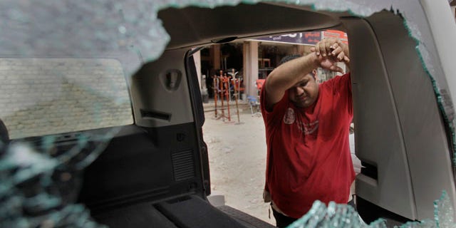 An Iraqi man inspects his damaged car at the site of a roadside bomb attack targeting a police patrol, killing and wounding a few civilians, police said, in central Baghdad, Iraq, Thursday, May 5, 2011. (AP Photo/Khalid Mohammed)