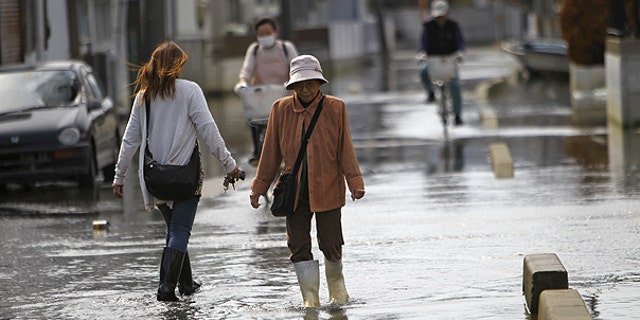 May 3: esidents stroll in a flooded street in Ishinomaki, Miyagi Prefecture, Japan. The area in this part of the city sunk nearly 2 feet 7 inches (0.8 meter) following the March 11 earthquake and tsunami.