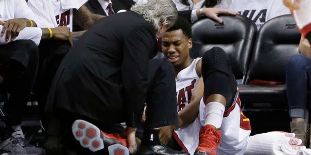 Miami Heat center Hassan Whiteside (21) is attended by a team member after he was injured during the first half of Game 3 of an NBA second-round playoff basketball series against the Toronto Raptors, Saturday, May 7, 2016, in Miami. (AP Photo/Alan Diaz)