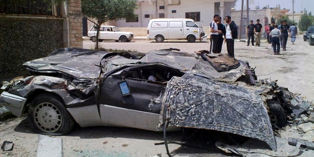 May 11: In this undated citizen journalism image made on a mobile phone and acquired by the AP, Syrians gather near a damaged car in the southern city of Daraa, Syria.