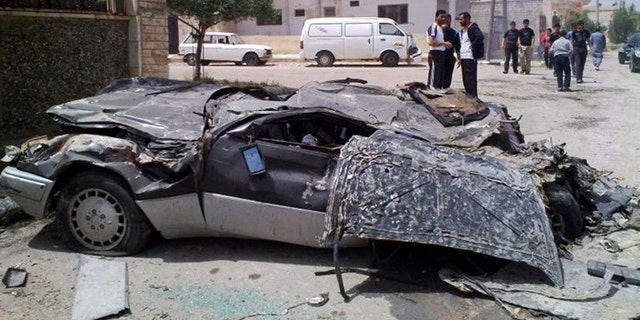 May 11: In this undated citizen journalism image made on a mobile phone and acquired by the AP, Syrians gather near a damaged car in the southern city of Daraa, Syria.