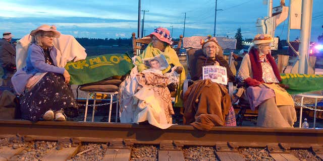 Members of the Seattle Raging Grannies sit in their rocking chairs chained together on the Burlington-Northern Railroad tracks at Farm to Market Road in Skagit County on Friday evening, May 13, 2016, in Burlington, Wash.