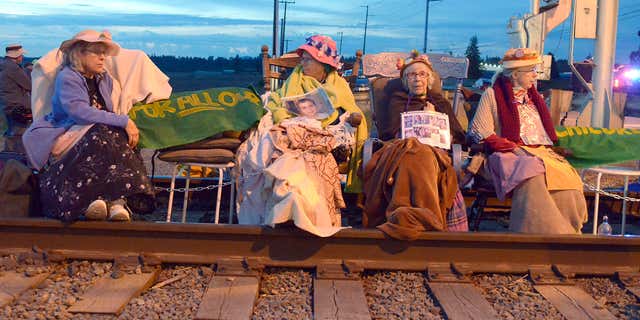 Members of the Seattle Raging Grannies sit in their rocking chairs chained together on the Burlington-Northern Railroad tracks at Farm to Market Road in Skagit County on Friday evening, May 13, 2016, in Burlington, Wash.