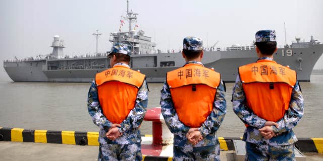 FILE - In this May 6, 2016, file photo, soldiers from the Chinese People's Liberation Army (PLA) Navy watch as the USS Blue Ridge arrives at a port in Shanghai.
