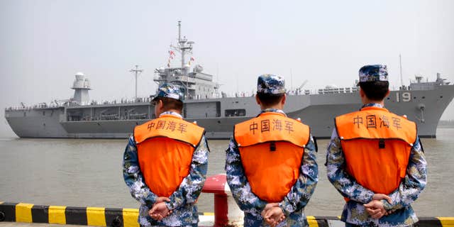 FILE - In this May 6, 2016, file photo, soldiers from the Chinese People's Liberation Army (PLA) Navy watch as the USS Blue Ridge arrives at a port in Shanghai.