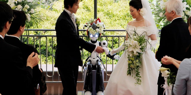 May 16: The 'I-Fairy' wears a wreath of flowers as it directs a wedding ceremony for groom Tomohiro Shibata 42, and bride Satoko Inouye, 36, at a Tokyo restaurant.