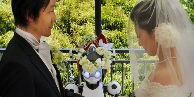 May 16: Bride Satoko Inouye, 36, puts a ring on a finger of her groom Tomohiro Shibata 42, as I-Fairy, a four-foot tall seated robot, wearing a wreath of flowers, directs their wedding ceremony at a Tokyo restaurant.