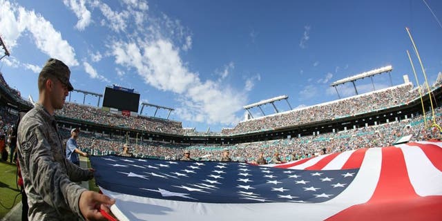 of the game at Sun Life Stadium on November 22, 2015 in Miami Gardens, Florida.,MIAMI GARDENS, FL - NOVEMBER 22: Memebers of the US Armed Forces hold an American Flag on the field for the singing of God Bless America during the second quarter of the game between the Miami Dolphins and the Dallas Cowboys at Sun Life Stadium on November 22, 2015 in Miami Gardens, Florida. (Photo by Rob Foldy/Getty Images)