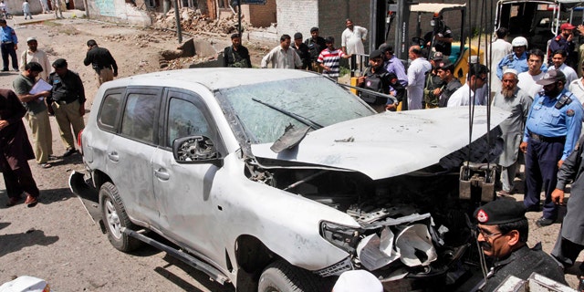 May 20: Pakistani police officers gather around a vehicle damaged in a roadside bomb explosion in Peshawar, Pakistan.