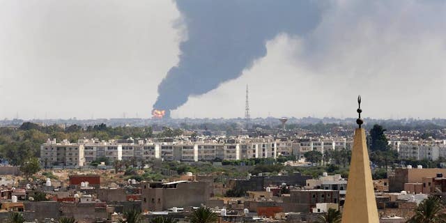 Black smoke billows over the skyline as a fire at the oil depot for the airport rages out of control after being struck in the crossfire of warring militias battling for control of the airfield, in Tripoli, Libya Monday, July 28, 2014. The latest violence to plague the country has so far killed scores of people and wounded hundreds as foreigners flee the chaos. Libya's interim government said in a statement that the fire could trigger a "humanitarian and environmental disaster" in Tripoli, appealing for "international help" to extinguish the inferno. (AP Photo/Mohammed Ben Khalifa)