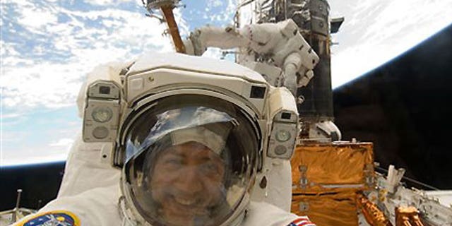 Astronaut Mike Massimino is photographed through a window of the Space Shuttle Atlantis - file photo.