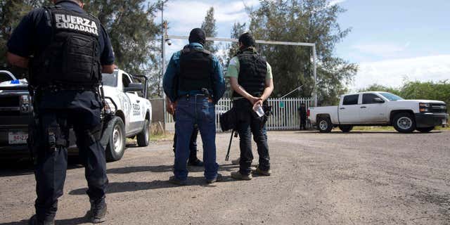 May 22, 2015: Mexican state police stand guard at the entrance of Rancho del Sol, near Vista Hermosa, Mexico.
