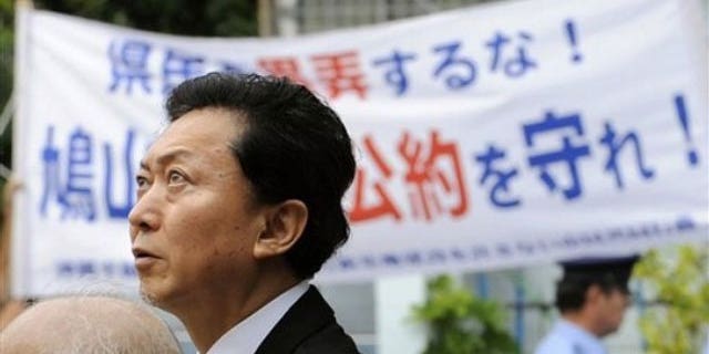 May 23: Japanese Prime Minister Yukio Hatoyama passes by a banner reading "Keep the promise" in Naha during his tour of Okinawa, Japan.