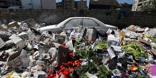 A car is seen between a pile of garbage covered with white pesticide in the Palestinian refugee camp of Sabra in Beirut, Lebanon, Thursday, July 23, 2015. The Lebanese cabinet has failed to agree on a solution for the country’s growing garbage crisis, postponing discussion until next week as trash piles up on the streets. (AP Photo/Bilal Hussein)