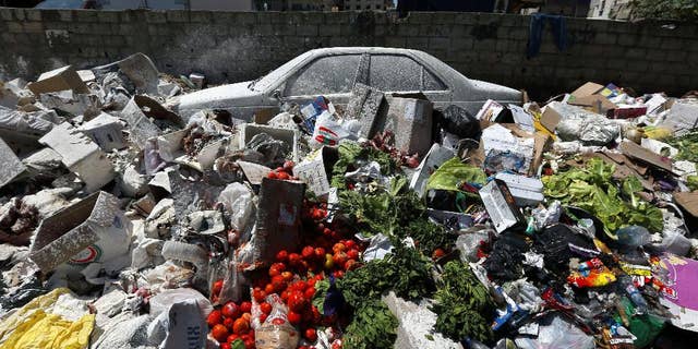 A car is seen between a pile of garbage covered with white pesticide in the Palestinian refugee camp of Sabra in Beirut, Lebanon, Thursday, July 23, 2015. The Lebanese cabinet has failed to agree on a solution for the country’s growing garbage crisis, postponing discussion until next week as trash piles up on the streets. (AP Photo/Bilal Hussein)