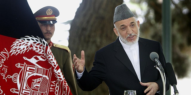 May 24: Afghan President Hamid Karzai, right, addresses a joint press conference with NATO Secretary General Anders Fogh Rasmussen, unseen, as an Afghan Presidential bodyguard holds the Afghan flag, left, at the Presidential palace in Kabul, Afghanistan.