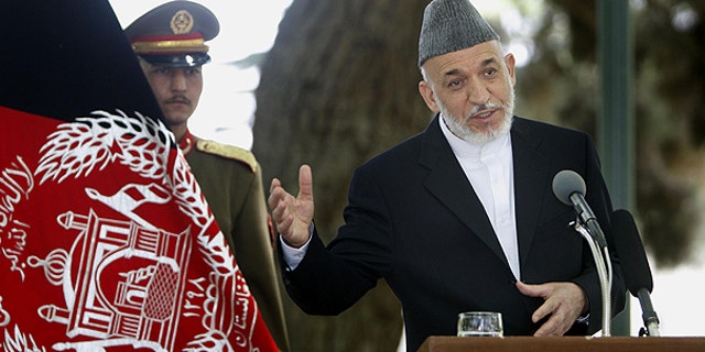 May 24: Afghan President Hamid Karzai, right, addresses a joint press conference with NATO Secretary General Anders Fogh Rasmussen, unseen, as an Afghan Presidential bodyguard holds the Afghan flag, left, at the Presidential palace in Kabul, Afghanistan.