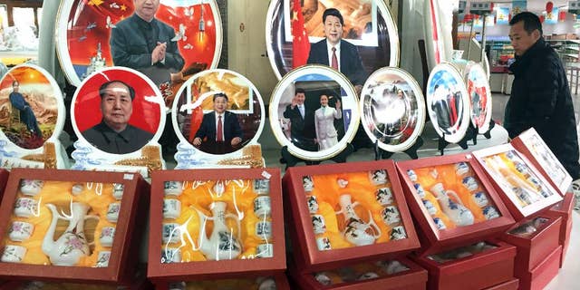 In this photo taken Friday, Dec. 30, 2016, a Chinese man walks past ceramic plates with images of Chinese President Xi Jinping displayed at a rest stop near Beijing. During his annual New Year Eve's speech, Chinese President Xi Jinping says his government will continue to focus on poverty alleviation at home and resolutely defending China's territorial rights on the foreign front. (AP Photo/Ng Han Guan)