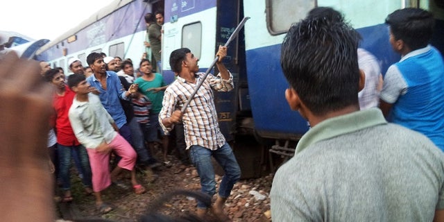 A volunteer breaks the glass of a train compartment window to rescue passengers trapped after an accident near Khatauli, in the northern Indian state of Uttar Pradesh, Saturday, Aug. 19, 2017. Six coaches of a passenger train derailed in northern India on Saturday, killing more than 20 people and injuring dozens, officials said. (AP Photo)