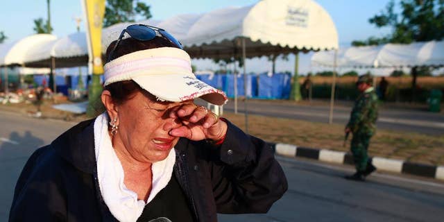 A pro-government demonstrator cries as she leaves a demonstration site after soldiers staged a coup Thursday, May 22, 2014 on the outskirts of Bangkok, Thailand. Thailand's new military junta has announced that it has suspended the country's constitution. A military statement broadcast on national television Thursday confirmed the nation's caretaker government is no longer in power but said the Senate will remain in place. (AP Photo/Wason Wanichakorn)