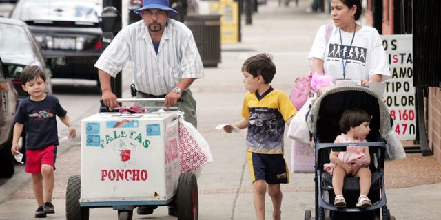 CHICAGO - JUNE 14: Residents walk past a paleta vendor along 26th Street in the predominantly Mexican Little Village neighborhood June 14, 2005 in Chicago, Illinois. According to the U.S. census Hispanics accounted for approximately half of the national population growth between July 1, 2003 and July 1, 2004 now accounting for one-seventh of the population. (Photo by Scott Olson/Getty Images)