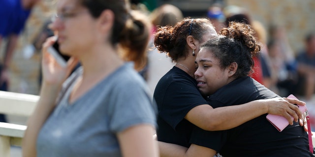 Students console each other following a school shooting at Santa Fe High School.