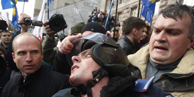 A Ukrainian opposition activist grabs the helmet of a riot policeman during clashes in Kiev, on October 2, 2013