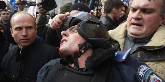 A Ukrainian opposition activist grabs the helmet of a riot policeman during clashes in Kiev, on October 2, 2013