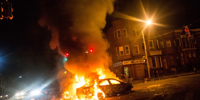 BALTIMORE, MD - APRIL 27:  Two cars burn in the middle of an intersection at New Shiloh Baptist Church on April 27, 2015 in Baltimore, Maryland. Riots have erupted in Baltimore following the funeral service for Freddie Gray, who died last week while in Baltimore Police custody.  (Photo by Andrew Burton/Getty Images)