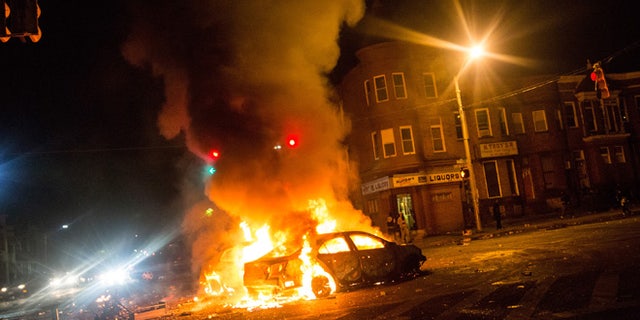 BALTIMORE, MD - APRIL 27: Two cars burn in the middle of an intersection at New Shiloh Baptist Church on April 27, 2015 in Baltimore, Maryland. Riots have erupted in Baltimore following the funeral service for Freddie Gray, who died last week while in Baltimore Police custody. (Photo by Andrew Burton/Getty Images)