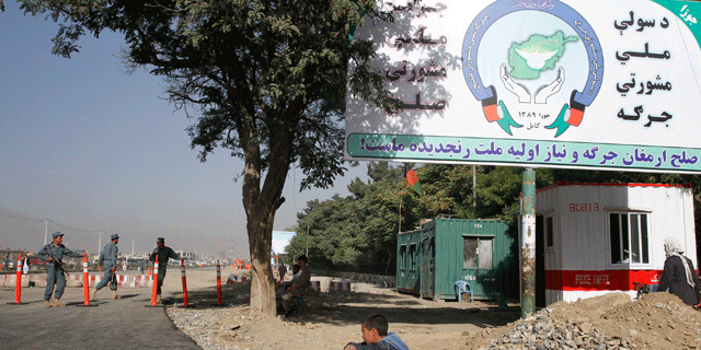 June 1: Afghan policemen stand guard at a check point of the peace meeting tent, near a billboard advertising the three-day conference in Kabul.